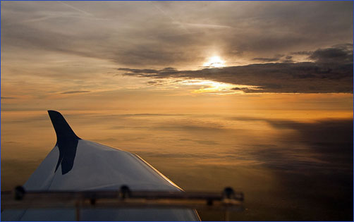 Blick aus einem Flugzeug auf einen Sonnenuntergang über den Wolken
